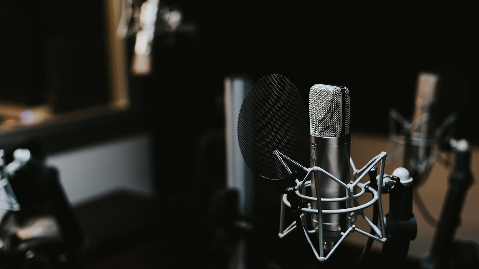 Condenser microphone in a shock mount with a pop filter in a dim recording studio